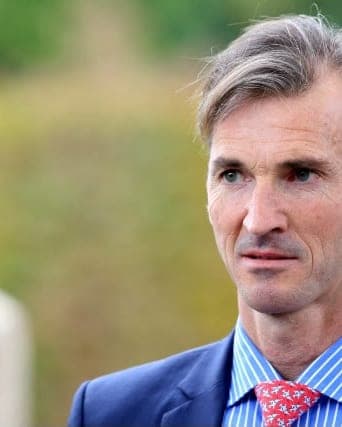 François Monfort in a blue striped shirt and red tie, photographed outdoors