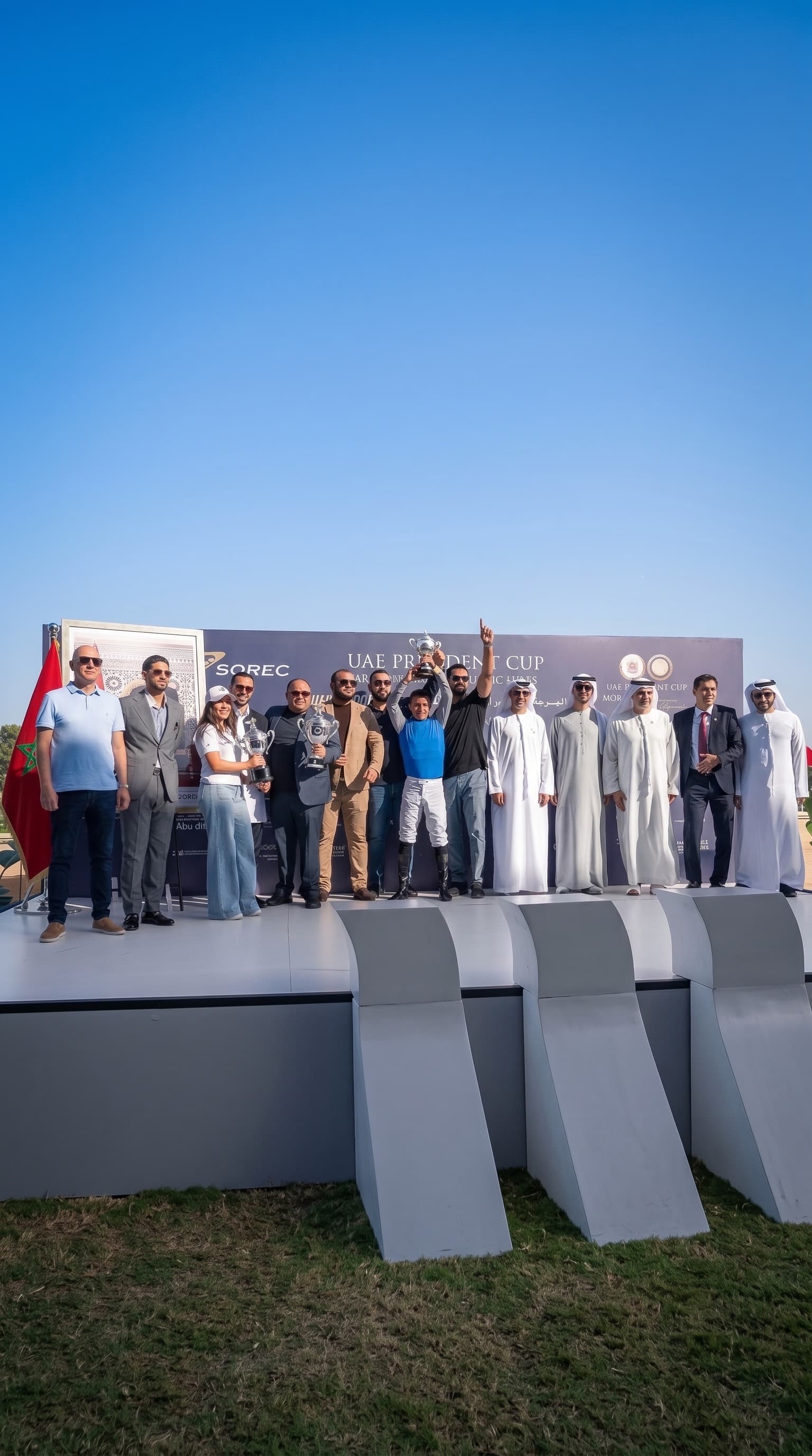 The Al Leith Racing team and guests on the podium at the UAE President Cup in Morocco, the jockey holding the trophy overhead